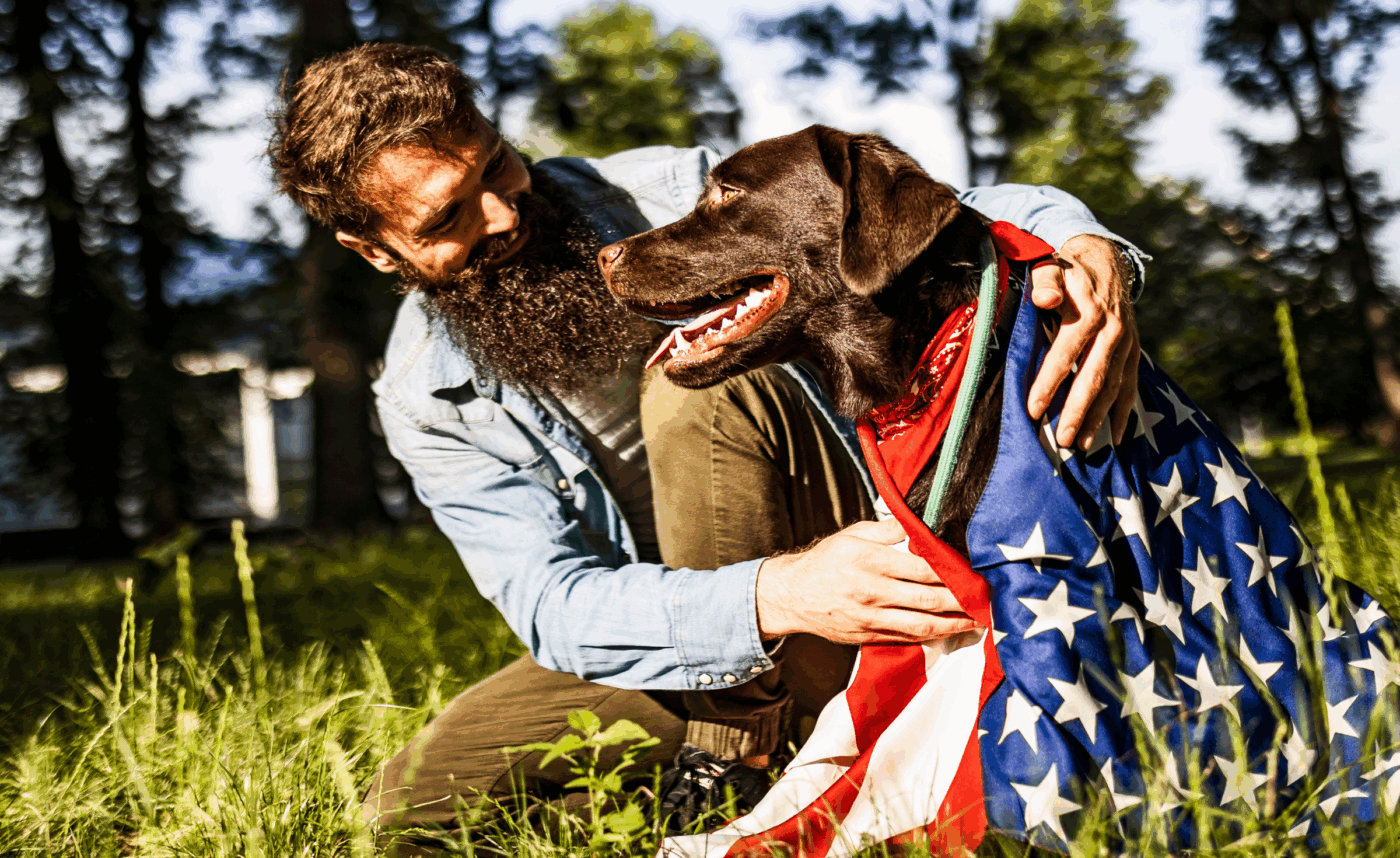 Man hugs dog with American flag wrapped around it